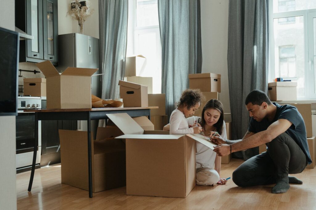 Family with a toddler unpacking moving boxes in their new kitchen