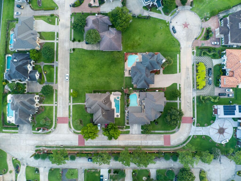 Aerial view of a suburban neighborhood with lawns and backyard pools