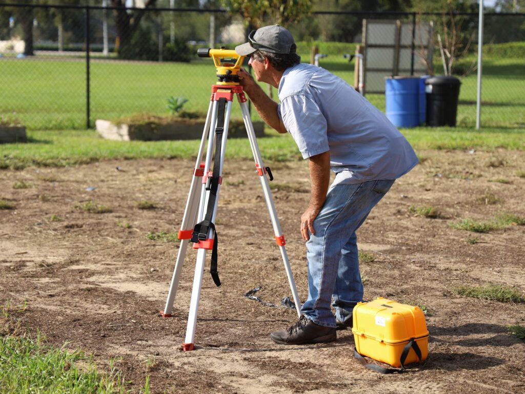 Surveyor measuring a cleared lot during preschool franchise site selection