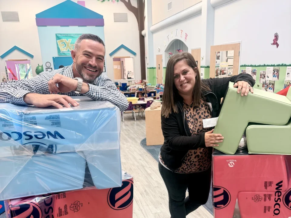 Nick and Amanda Rolon, the new owners of Creative World School in St. Cloud, smiling beside stacks of new soft play blocks inside the school